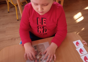 Chłopiec układa z części obrazek z Mikołajem.
